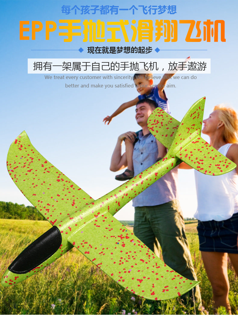 Green and red speckled airplane toy with family in a field